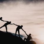 A group of people silhouetted against a sunrise, representing teamwork and connection at the Fiji Educators Conference 2026.