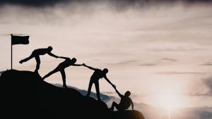 A group of people silhouetted against a sunrise, representing teamwork and connection at the Fiji Educators Conference 2026.